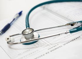 A stethoscope and pen resting on a medical report in a healthcare setting.